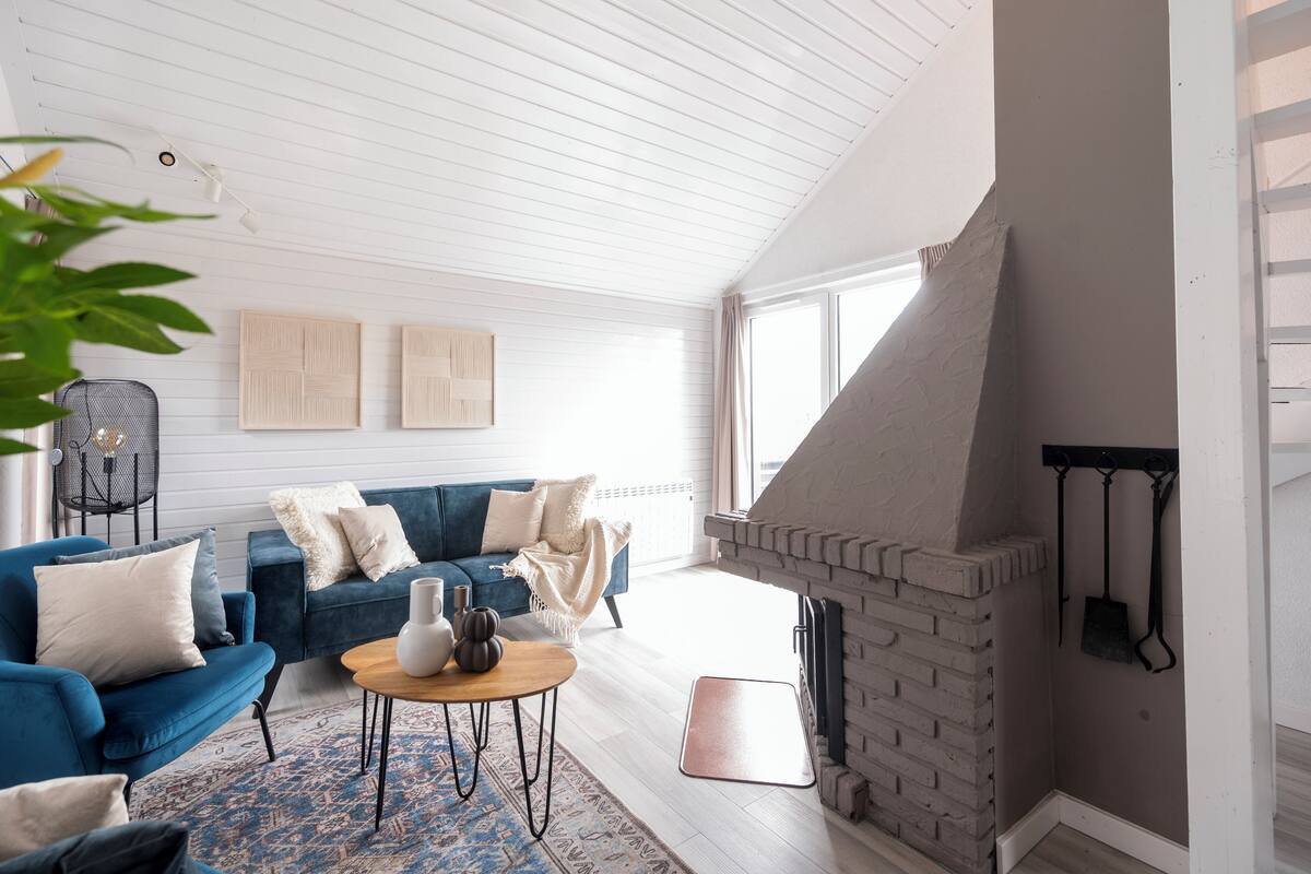 A modern living room with a blue sofa, a coffee table, and a fireplace.