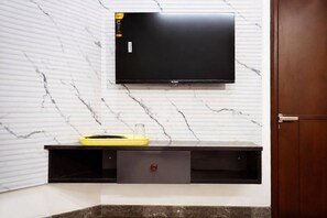 A wall-mounted television, a yellow tray, and a wooden door. - Royal Suites Outer Ring Road Bellandur - Bangalore (Bengaluru)