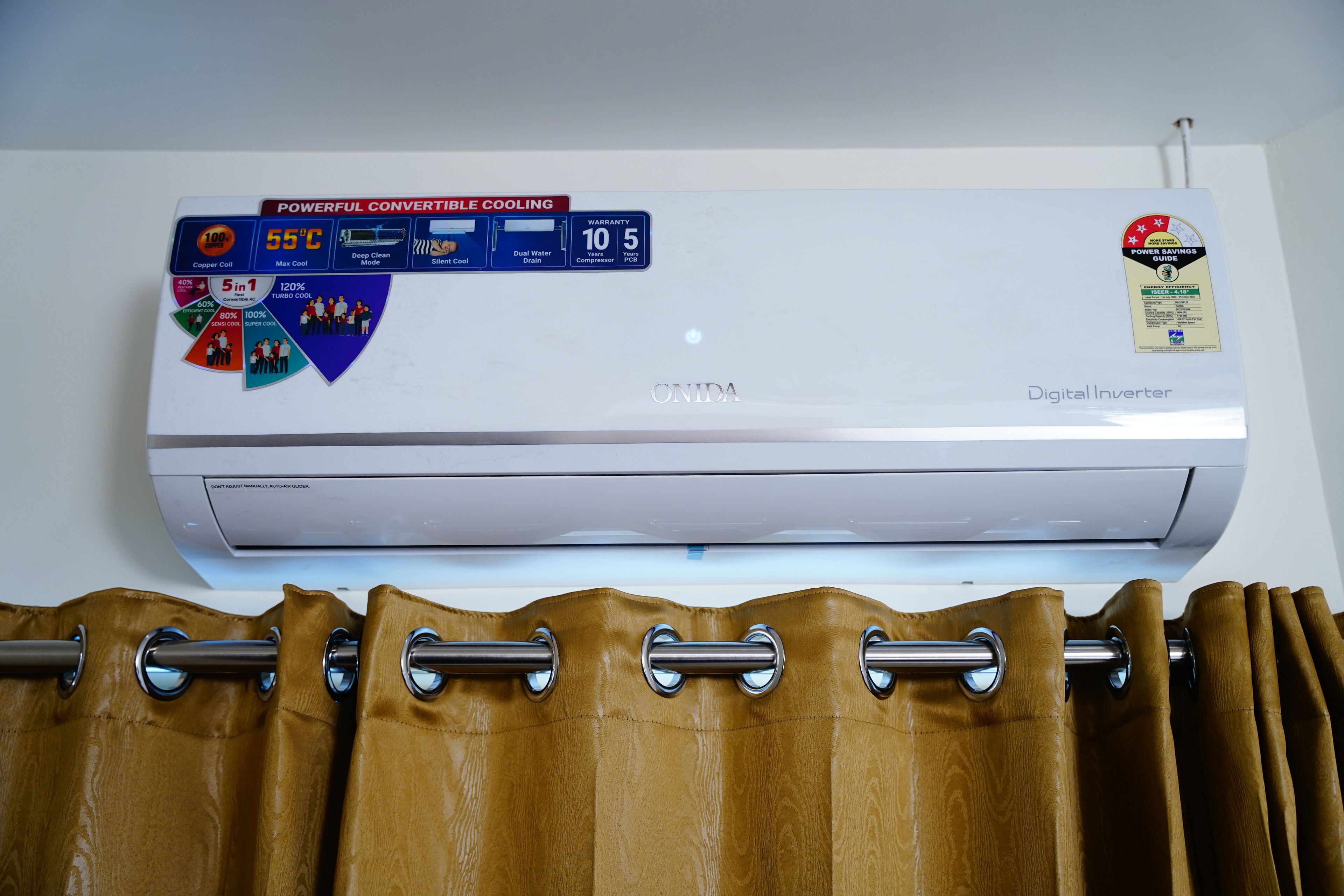 A wall-mounted digital inverter air conditioner with a control panel displaying various cooling modes and a warranty sticker.