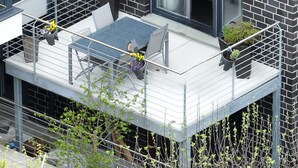 A balcony with a table and chairs, potted plants, and a view of the surrounding area.