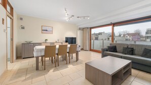 Un salon moderne comprenant un canapé, une table basse et un coin repas avec des chaises et une table.