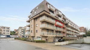 A multi-story residential building with balconies, a parking area, and a visible entrance. - 3 bedroom accommodation in Oostduinkerke (Oostduinkerke)
