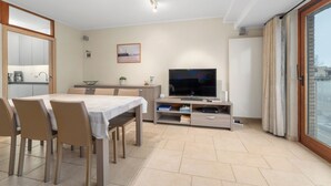 Un salon moderne comprenant un coin repas, un téléviseur à écran plat et une porte-fenêtre coulissante donnant sur l’extérieur.