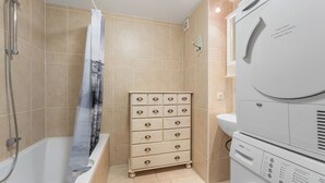 A bathroom with a bathtub, shower, and stacked washer and dryer. - 3 bedroom accommodation in Oostduinkerke (Oostduinkerke)