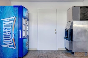 Una habitación con un dispensador de agua azul Aquafina, una puerta blanca y un electrodoméstico de acero inoxidable.