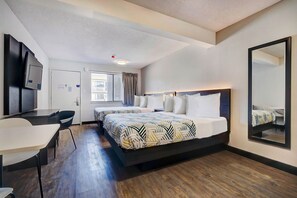 Une chambre d’hôtel avec un grand lit, un bureau, une chaise, une télévision et une fenêtre avec des rideaux.