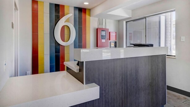 A reception area with a large number '6' on the wall, a counter, and a window with a view. - Studio6 Rock Springs, WY - Flaming Gorge (Rock Springs)