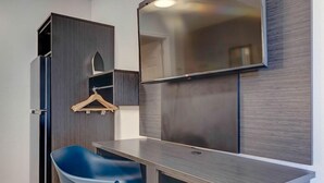 A compact room with a desk, a chair, a wardrobe, and a mirror. - Studio6 Rock Springs, WY - Flaming Gorge (Rock Springs)