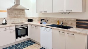 Een moderne keuken met witte kasten, een inbouwoven, een vaatwasser en een spoelbak.