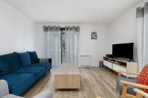 A modern living room with a sofa, a coffee table, a TV stand, and a chair.