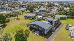 A residential area with modern houses, a large lawn, and a view of the sea. - Beach House @ 406 - Matarangi (Matarangi)