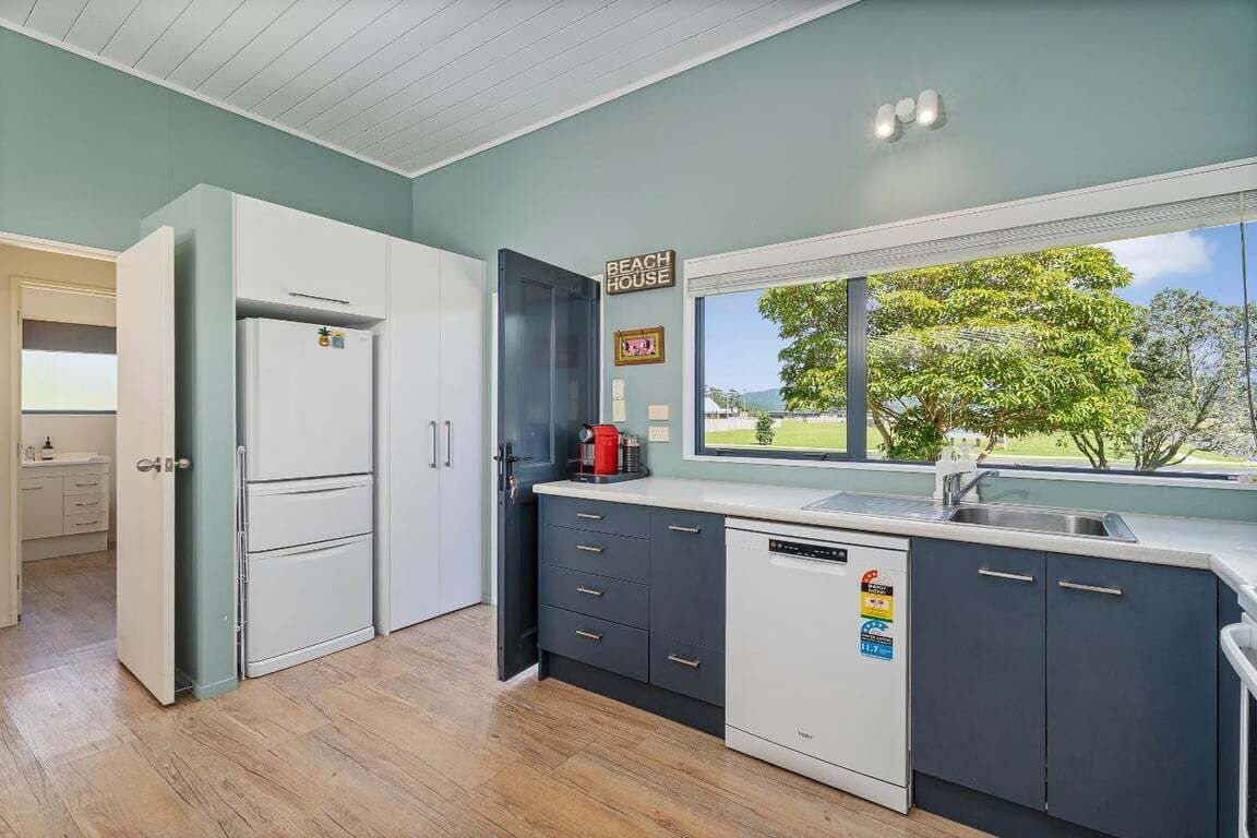 A modern kitchen with a view of a green landscape, a coffee machine, and a dishwasher.