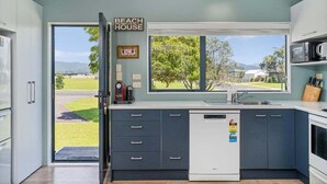 A modern kitchen with a view of the outdoors, a dishwasher, and a sign reading "BEACH HOUSE". - Beach House @ 406 - Matarangi (Matarangi)