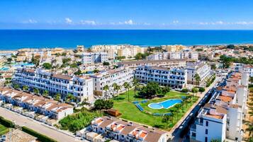 A coastal hotel with multiple buildings, a swimming pool, and a view of the sea.