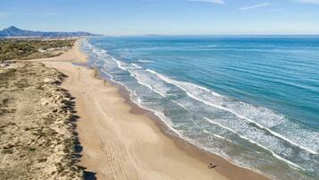 A beach with a clear view of the ocean and a distant mountain range.