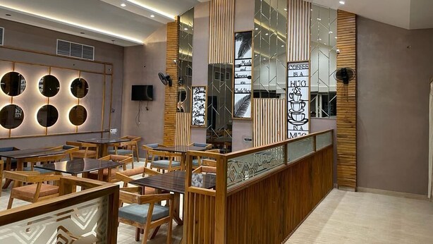 A modern cafe with wooden furniture and a central counter. - Riviera Resort and Hotels (Durg)