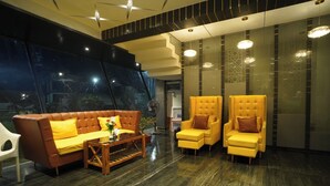 A lobby with a brown leather sofa, a wooden coffee table, and two yellow armchairs. - Riviera Resort and Hotels (Durg)