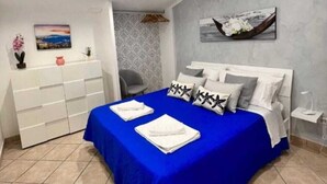 Quarto com cama, cômoda, cadeira e um quadro na parede.