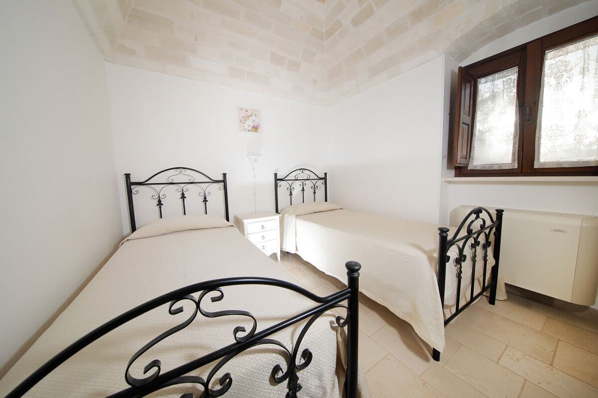 Une chambre avec deux lits, une fenêtre, un radiateur et un plafond en briques.