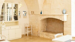 A stone fireplace, white furniture, and a cabinet with bottles. - Trulli Arco Antico (Locorotondo)