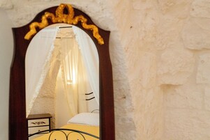 Un dormitorio con una cama, una mesita de noche y un espejo con marco decorativo.