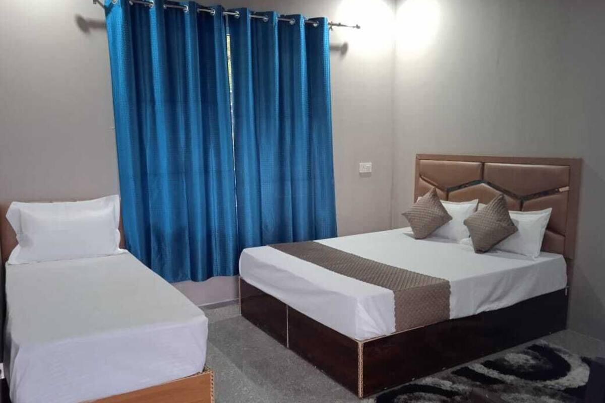 Un dormitorio con dos camas individuales, cabeceros y una cortina azul.