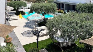 A residential area with a swimming pool, outdoor seating, and a view of the surrounding landscape. - OLIVIA RESORT (Thasos)