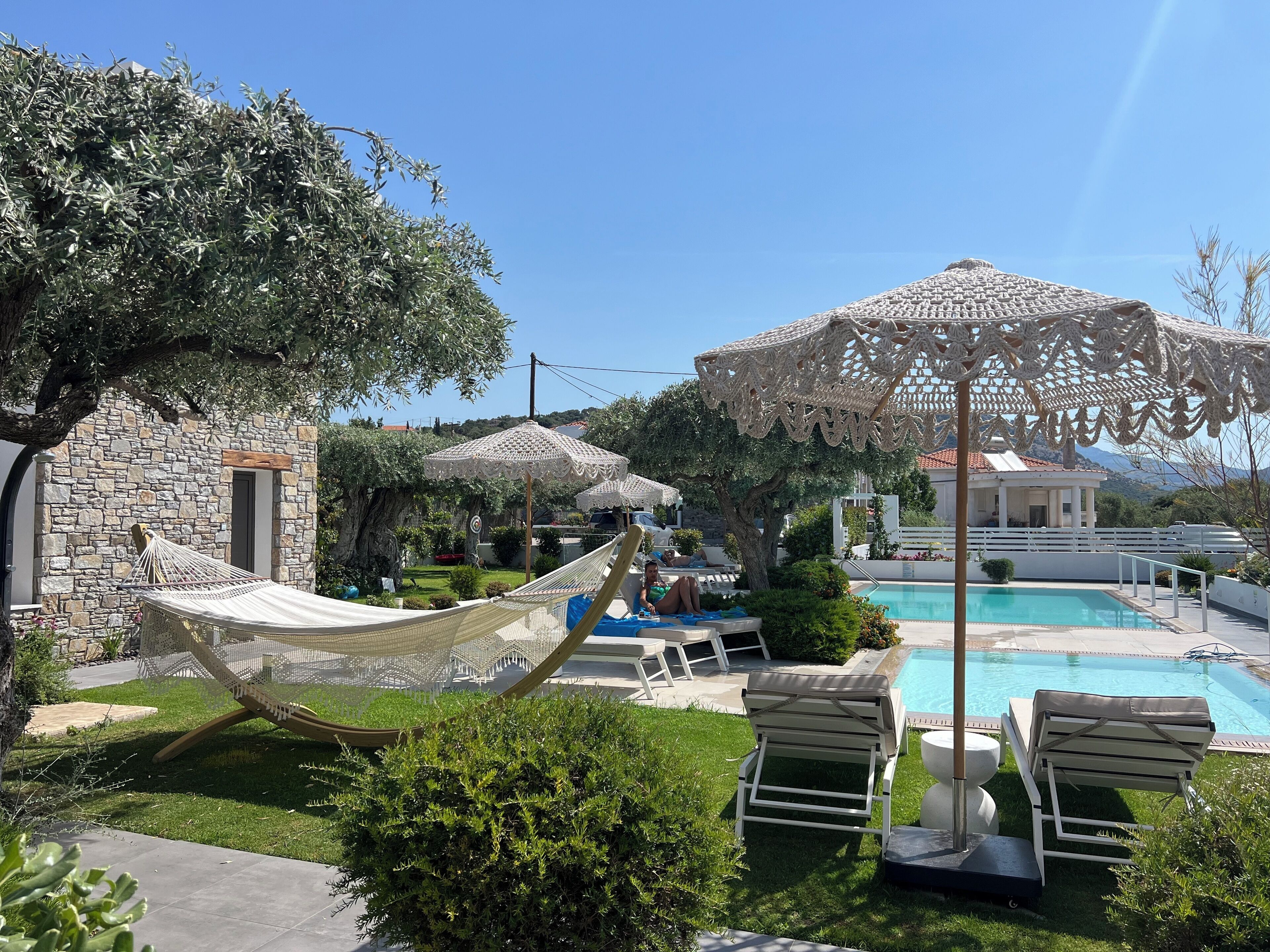 A poolside area with a hammock, lounge chairs, and a pool.