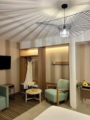 Une chambre dâhĂŽtel Ă©quipĂ©e dâun lit, dâune chaise, dâune table, dâun tĂ©lĂ©viseur, dâune armoire et dâun luminaire au plafond au design original.