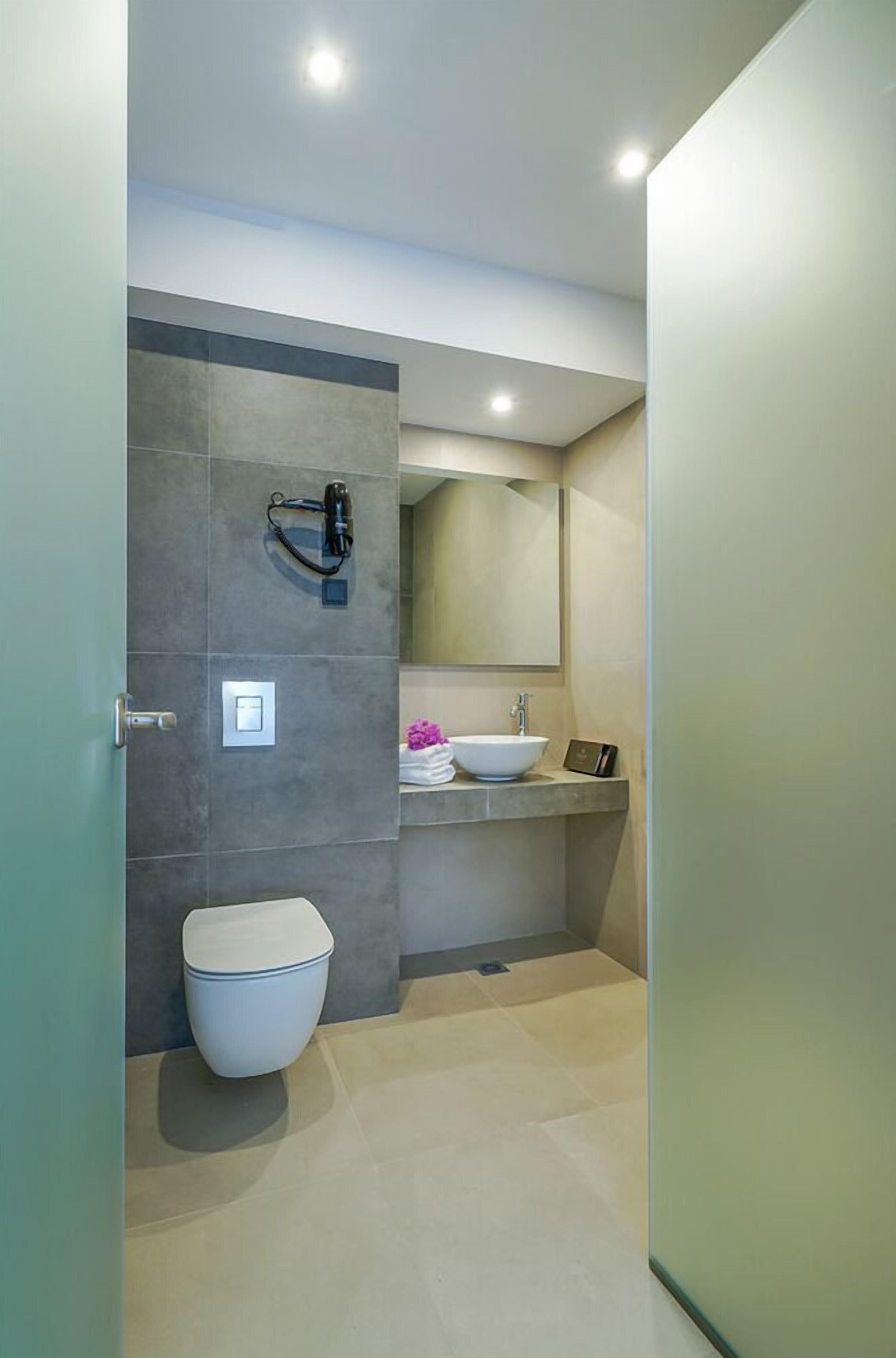 A modern bathroom with a toilet, sink, and mirror.