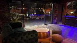 Zona relax moderna con un divano verde, poggiapiedi rotondi e una porta vetrata che dà su uno spazio esterno.