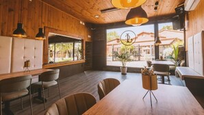 Un ristorante con pareti in legno, ampie finestre e un tavolo centrale circondato da sedie.