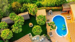 Una vista aerea di un resort con piscina, palme e zone relax all'aperto.