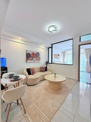 A modern living room with a sofa, coffee table, dining table, and chairs. - Cozy 1-bedroom apartment in fantastic Nairobi Westlands with AC and gym access (Nairobi)