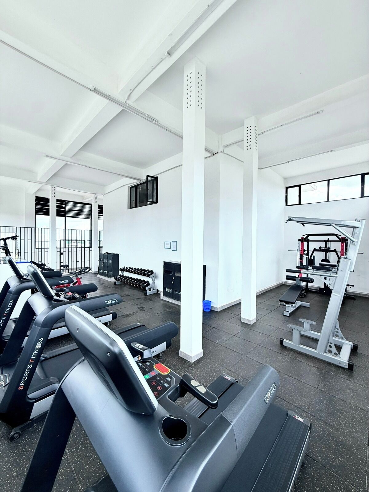 Un gimnasio con cintas de correr, mancuernas y máquinas de pesas.
