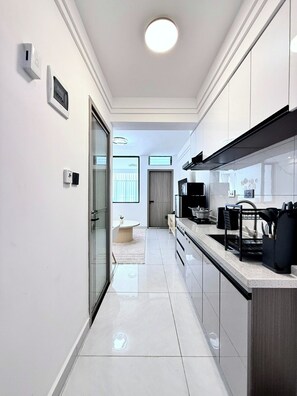 A modern kitchen with a central island, a built-in oven, and a black dish rack. - Cozy 1-bedroom apartment in fantastic Nairobi Westlands with AC and gym access (Nairobi)