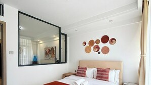Ett modernt hotellrum med en stor säng, en spegel, dekorationer på väggen och en förvaringslåda.