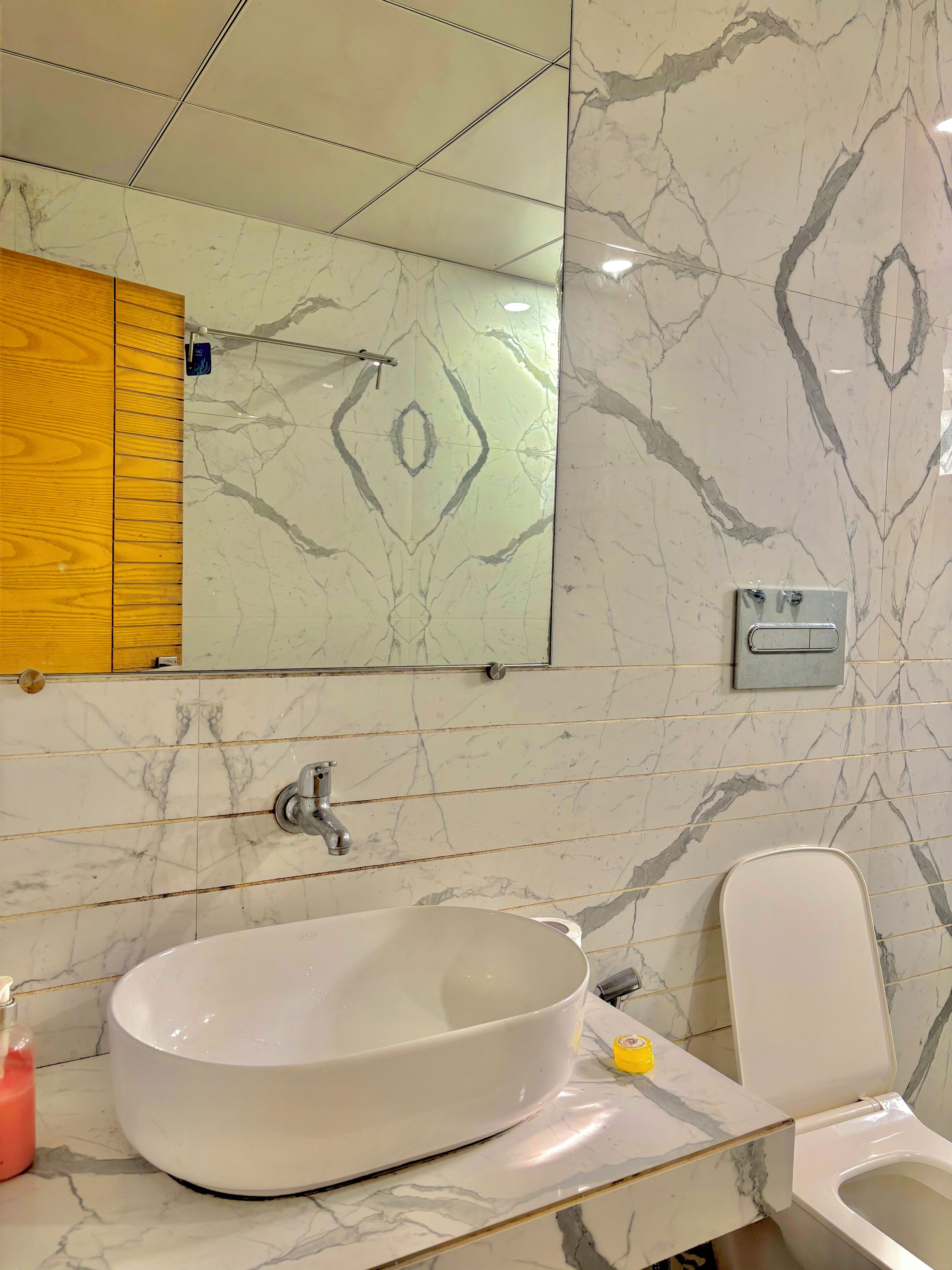 Ein Badezimmer mit einem großen Spiegel, einem weißen Waschbecken und einer Toilette.