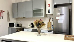 Une cuisine moderne avec des meubles gris, un réfrigérateur en acier inoxydable, un four à micro-ondes et un îlot central doté de deux tabourets de bar.