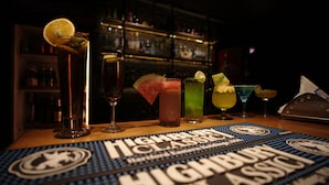 A bar with various drinks and a menu titled "Highbrow Classic" on a table. - HOTEL DE GRAND MALABAR (Kozhikode)