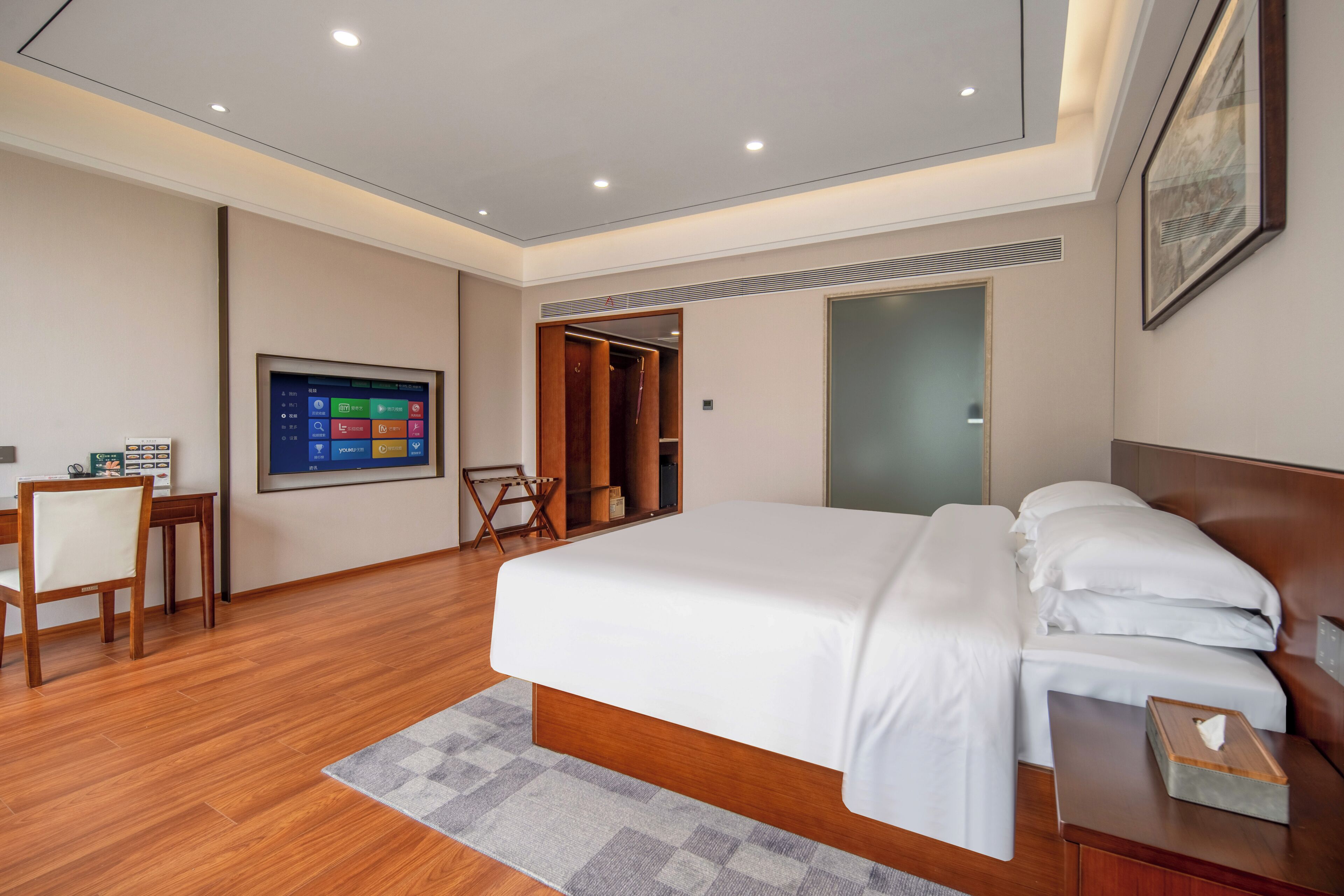 Une chambre d’hôtel moderne équipée d’un grand lit, d’un bureau avec une chaise, d’une télévision et d’une armoire.