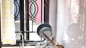 Une cuisine équipée d’un évier, d’un égouttoir et d’une bouteille de gaz.