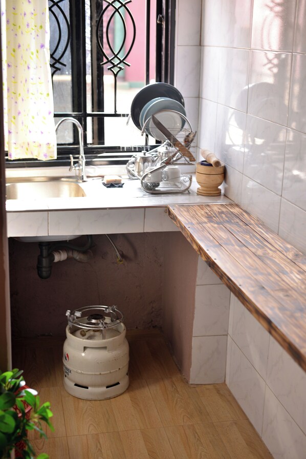 A kitchen with a sink, dish rack, and a gas cylinder.