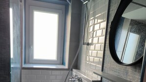 Een moderne badkamer met douche, wastafel en raam.