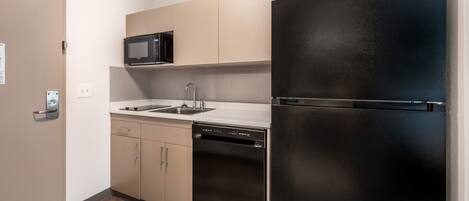 A compact kitchen with a black refrigerator, a microwave, and a dishwasher.