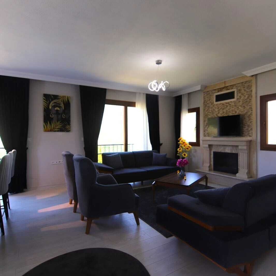 A modern living room with a sofa, armchairs, a fireplace, and a painting on the wall.