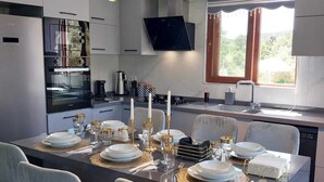 A modern kitchen with a central island, white cabinetry, and a flat-screen TV mounted above the island.
