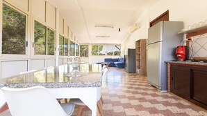 Una cocina moderna con encimera de granito, sillas blancas, un sofá azul y un refrigerador.