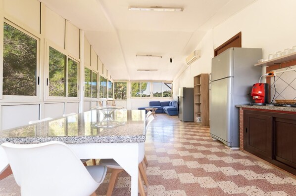 A modern kitchen with a granite countertop, white chairs, a blue sofa, and a refrigerator.