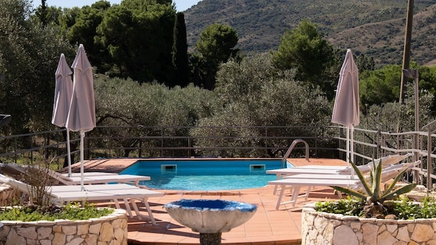 Un área de piscina con una fuente, sillas de descanso y sombrillas.